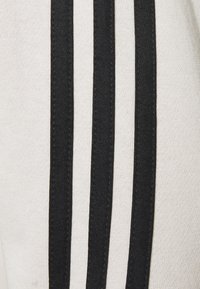 Gros plan sur un tissu blanc avec trois rayures noires verticales parallèles sur la surface.