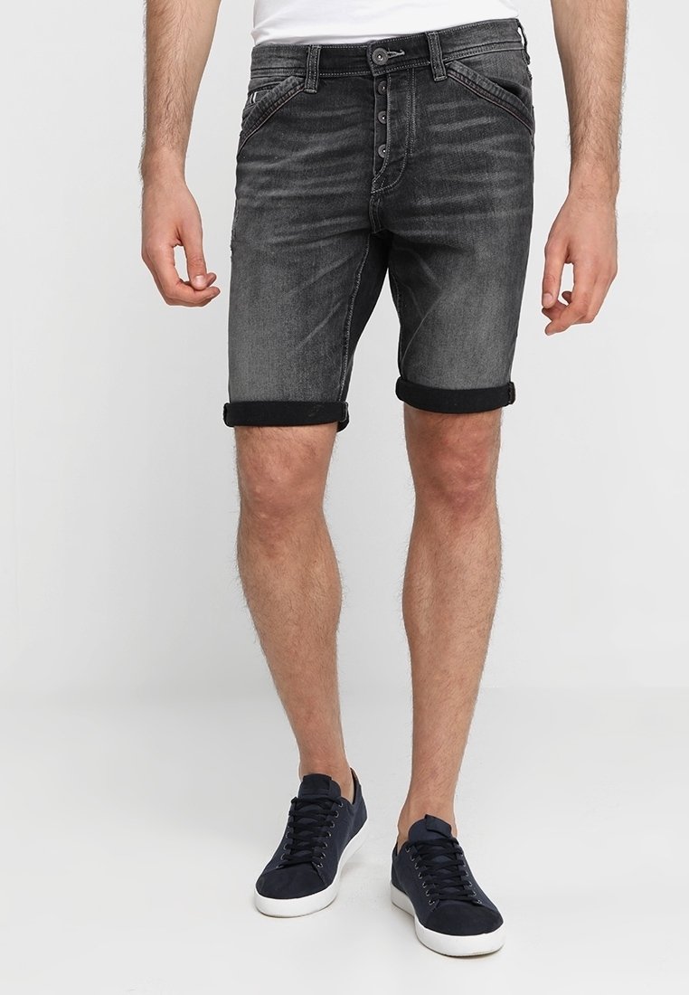 Ciemnoszare szorty dżinsowe z guzikowym zapięciem, z podwiniętymi mankietami, pięcioma kieszeniami i delikatnym wyblaknięciem. W połączeniu z ciemnymi trampkami.