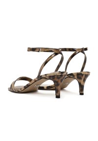 Sandały na obcasie w panterkę z cienkim paskiem w kostce i otwartym noskiem. Błyszczący materiał, niski obcas typu kitten heel, krzyżujący się design z tyłu.