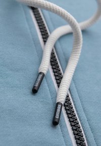 Jasnoniebieska bluza z kapturem z kontrastowym czarnym zamkiem. Białe sznurki zakończone czarnymi końcówkami z napisem "DIMBRE."