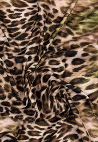 Tissu imprimé léopard avec une texture douce et lisse aux tons bruns, noirs et verts. Le motif comprend des taches irrégulières et des volutes.