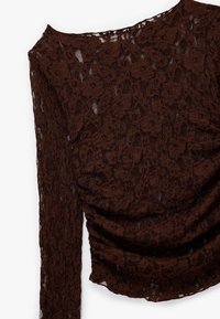 Bruine kant top met lange mouwen, off-the-shoulder ontwerp, gerimpeld detail aan de voorkant en een bloemmotief over de gehele stof.