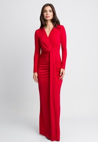 Czerwona sukienka z długim rękawem i dekoltem w kształcie litery V, z materiałem drapowanym, podąłem po bokach i prostą sylwetką. Miękka, gładka tekstura.