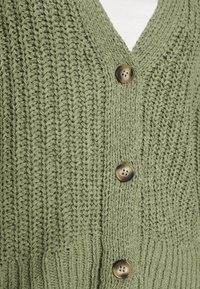 Grüne Strickjacke mit V-Ausschnitt, strukturiertem Stoff und drei braunen Knöpfen auf der Vorderseite.