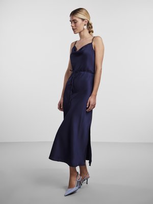 Abito in satin blu navy con scollatura a cappuccio, spalline regolabili e uno spacco laterale, abbinato a décolleté azzurro chiaro a punta.