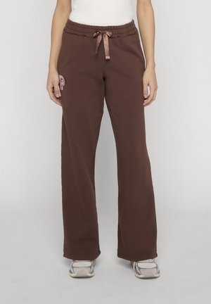 Brune sweatpants med lige ben, elastisk talje og satin snøre, båret med hvide sneakers og en hvid top.