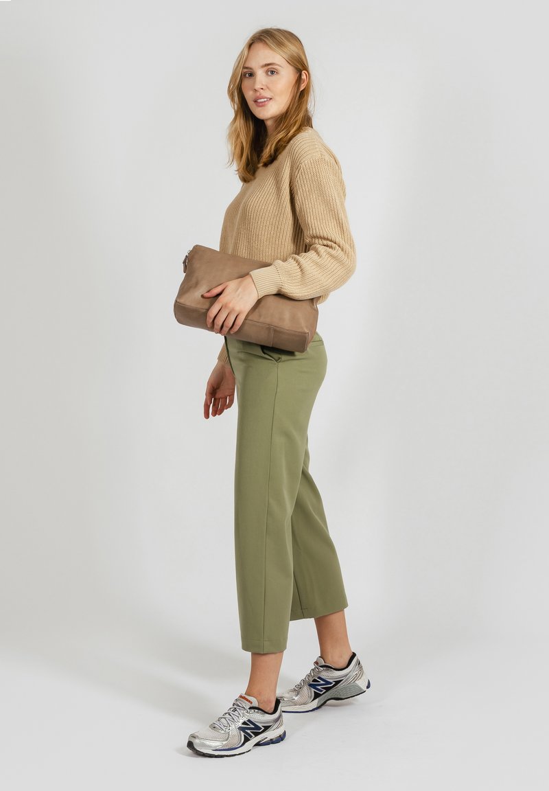 Beige csíkos pulóver, olajzöld cropped nadrág, ezüst torna cipő, és egy barna clutch táska. Egyszerű dizájn, texturált anyagokkal.