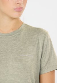 Olijfgroene t-shirt gemaakt van zachte, gestructureerde stof. Heeft een ronde hals en korte mouwen, met het logo "ENDURANCE" in lichtpaars op de voorkant.