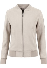 Giacca bomber beige in suede sintetico, dotata di chiusura frontale con zip, orlo a coste e tasca con zip sulla manica. Texture liscia e design strutturato.