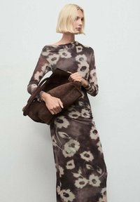 Rochie cu mânecă lungă, cu un model floral în nuanțe de maro, negru și crem. Modelul ține o geantă din suede maro închis. Textură netedă, siluetă ajustată.