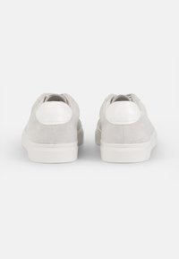Grey suede sneakers with white rubber soles, featuring a smooth white heel accent and a subtle texture. Classic low-top design.