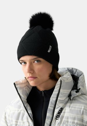 Cappellino a maglia nero con motivo strutturato e pon pon di pelliccia nera sulla sommità. Presenta una piccola etichetta con marchio sul lato.