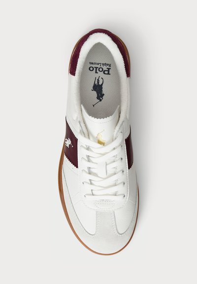 Witte sneaker met leren en suède materialen, bordeaux accentstrepen, platte veters en een bruine rubberen zool. Logo op de tong.