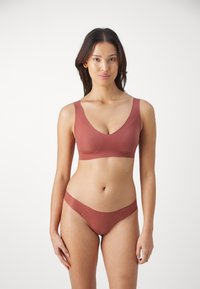 Trådløs BH og matchende truse i rustfarge. Glatt, stretchy stoff med sømløst design og minimalistisk detaljer.