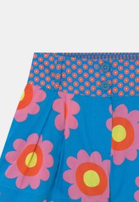 Pantaloni corti blu con motivo floreale, caratterizzati da grandi fiori rosa e cerchi gialli. Vita elasticizzata con due bottoni blu e un motivo coordinato.