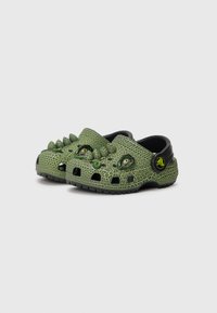 Roheline croc'i mudel tekstuursed pinnad, millel on väljaulatuvad okkad ja silmad, must rihm ja ventilatsiooniaugud õhuringluseks.