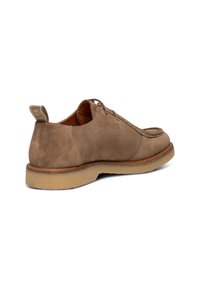 Scarpa bassa in suede taupe con lacci, punta rotonda, suola beige imbottita e linguetta sul tallone su sfondo bianco.