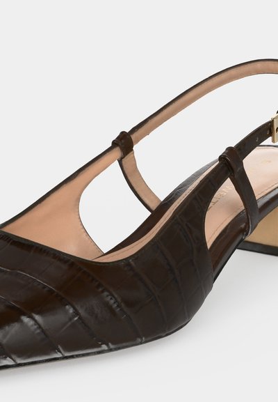 Gros plan sur un escarpin slingback marron foncé à texture crocodile, bout pointu, doublure beige et fine bride à la cheville.
