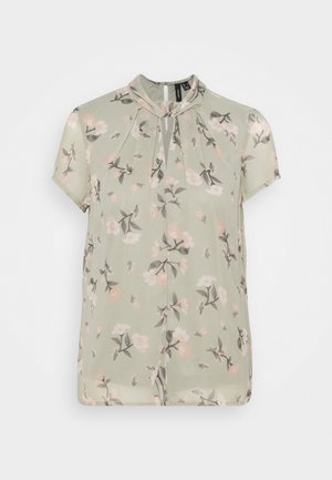 Korte mouwen blouse in lichtgroene stof met een bloemenpatroon van roze en grijze bloemen; geplooide details bij de halslijn.