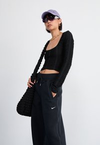 Must musträpiga mustade pikade varrukatega topp, millel on tekstuuriline disain, koos tumedate spordipükstega, millel on Nike logo. Aksessuaarideks lavendliserine kapuuts ja päikeseprillid.