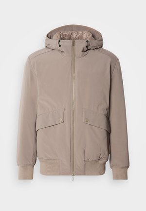 Světle béžová bomber bunda se zapínáním na zip, dvěma předními kapsami a kapucí. Má žebrované manžety a spodní lem, hladký povrch látky.