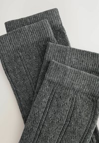 Calcetines de punto acanalado gris oscuro con un patrón texturizado, que presenta secciones elevadas y planas alternas. Material suave diseñado para mayor comodidad.