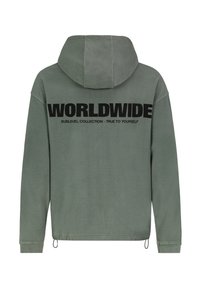 Groene, fleece hoodie met een relaxte pasvorm. Zwarte tekst op de achterkant leest "WORLDWIDE" en "SUBLEVEL COLLECTION - TRUE TO YOURSELF."