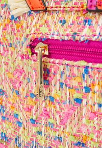 Vævet stråtaske med livlige tråde i pink, orange, blå og grøn. Har en lilla lynlås med en guldmetal trækklods og brandgraverede detaljer.