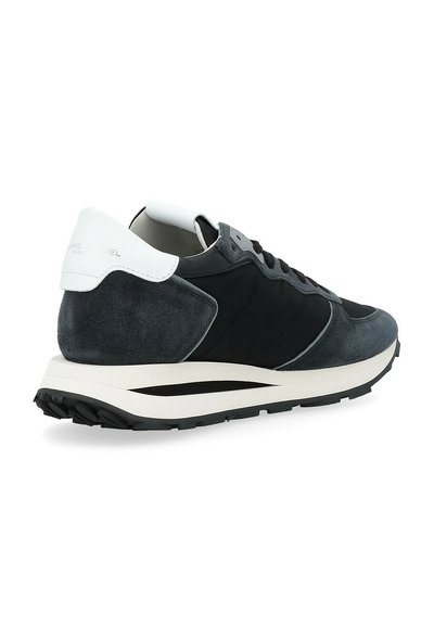 Sneaker da uomo in suede e pelle nera e grigia, con un accento sul tallone bianco, parte superiore testurizzata e una spessa suola in gomma nera.