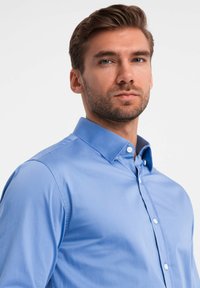 Lichtblauw button-up shirt met een gespreide kraag, gladde textuur, lange mouwen en witte knopen op de voorplacket.