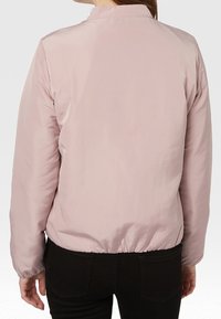 Lyserød, letvægtsjakke med rund krave, elastisk kant og glat stof. Har lange ærmer og minimal dekoration.