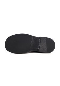 Semelle de chaussure habillée noire avec l'avant lisse et le talon texturé, montrant une plaque de talon fixée avec de petits clous sur fond blanc.