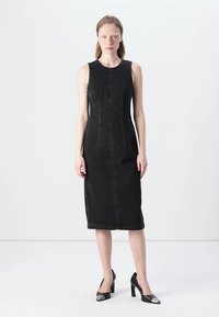 Black denim midi dress with a fitted silhouette, cap sleeves, and front seams. Worn with glossy black heels featuring silver accents.