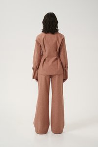 Dusty rose, long-sleeve jacket with a tailored fit and flared pants. The fabric has a textured finish and features accent hardware on sleeves.