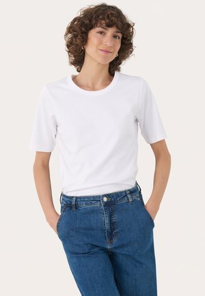 T-shirt bianco a maniche corte con scollo rotondo, abbinato a jeans di denim blu a vita alta con chiusura a bottone e tasche laterali.