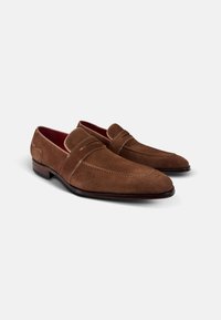 Bruine suède loafers met een spitse neus, gestikte details en een soepele leren zool. Het interieur heeft een contrasterende rode voering.