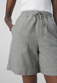 Shorts grigi con motivo a spina di pesce, dotati di una cintura elastica con cordoncino, tasche laterali e una vestibilità rilassata.