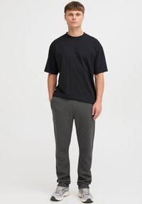 Black short-sleeve t-shirt paired with gray sweatpants, featuring a relaxed fit and soft fabric, worn with light-colored athletic shoes.