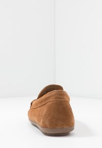 Mocassini in suede marrone con punta arrotondata e texture morbida. Suola piatta in gomma con cuciture lungo le giunture e design a caviglia bassa.