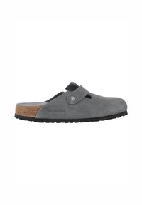 Clogs grises Birkenstock avec tige en suédine, semelle intermédiaire en liège et semelle extérieure en caoutchouc noir. Dispose d'une sangle avec une boucle en métal et d'un dos ouvert.