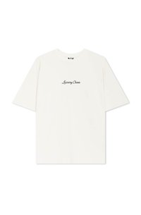 Camiseta de algodón blanca con mangas cortas y cuello redondo. En la parte delantera tiene impreso "Luxury Chaos" en texto cursivo negro.