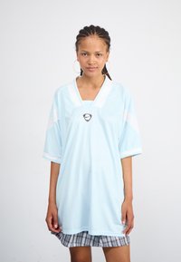 Lyseblå T-shirt med korte ærmer, der har en V-hals, hvide detaljer og et centralt logo. Teksturen ser glat ud med en mønsterfinish.