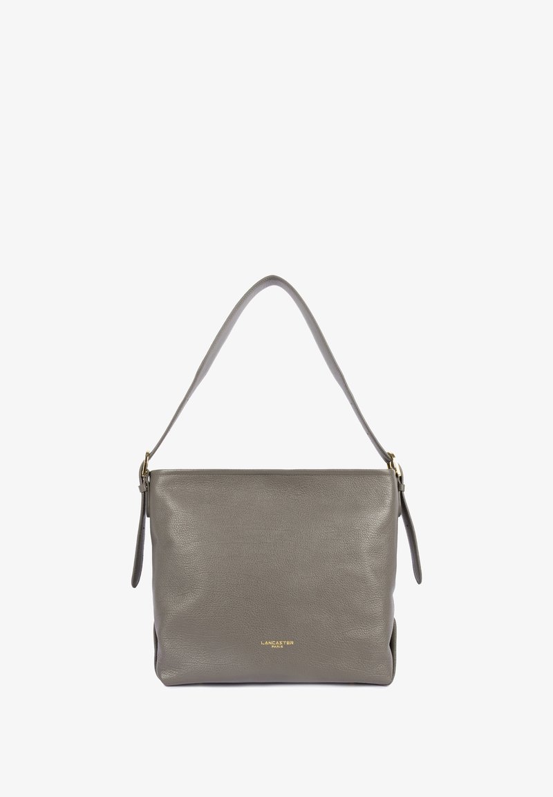 Sac à main en cuir gris avec une bandoulière arrondie, doté d'une fermeture éclair et d'un logo doré en relief sur le devant. Texture lisse.