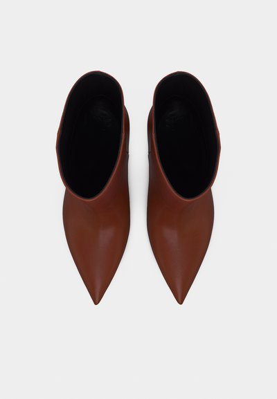 Ζεύγος καφέ μυτερών μποτάκια αστραγάλου με λείο δερμάτινο φινίρισμα, σε άποψη από πάνω πάνω σε λευκό φόντο.