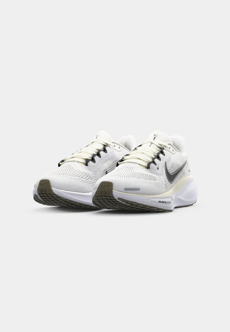 Zapatillas deportivas blancas con parte superior de malla, cordones negros y detalles en el swoosh, y una suela de goma texturizada. Presenta un cuello acolchado y amortiguación Air Zoom.