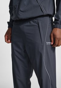 Donkergrijze sportbroek met een gestructureerde afwerking, met een slim fit, elastische tailleband, zijzakken en contrasterende grijze zijpaspels.