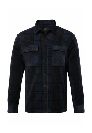 Camisa de franela con un patrón de cuadros en azul oscuro y negro, dos bolsillos en el pecho, cierre de botón y mangas largas. Textura suave y corte regular.