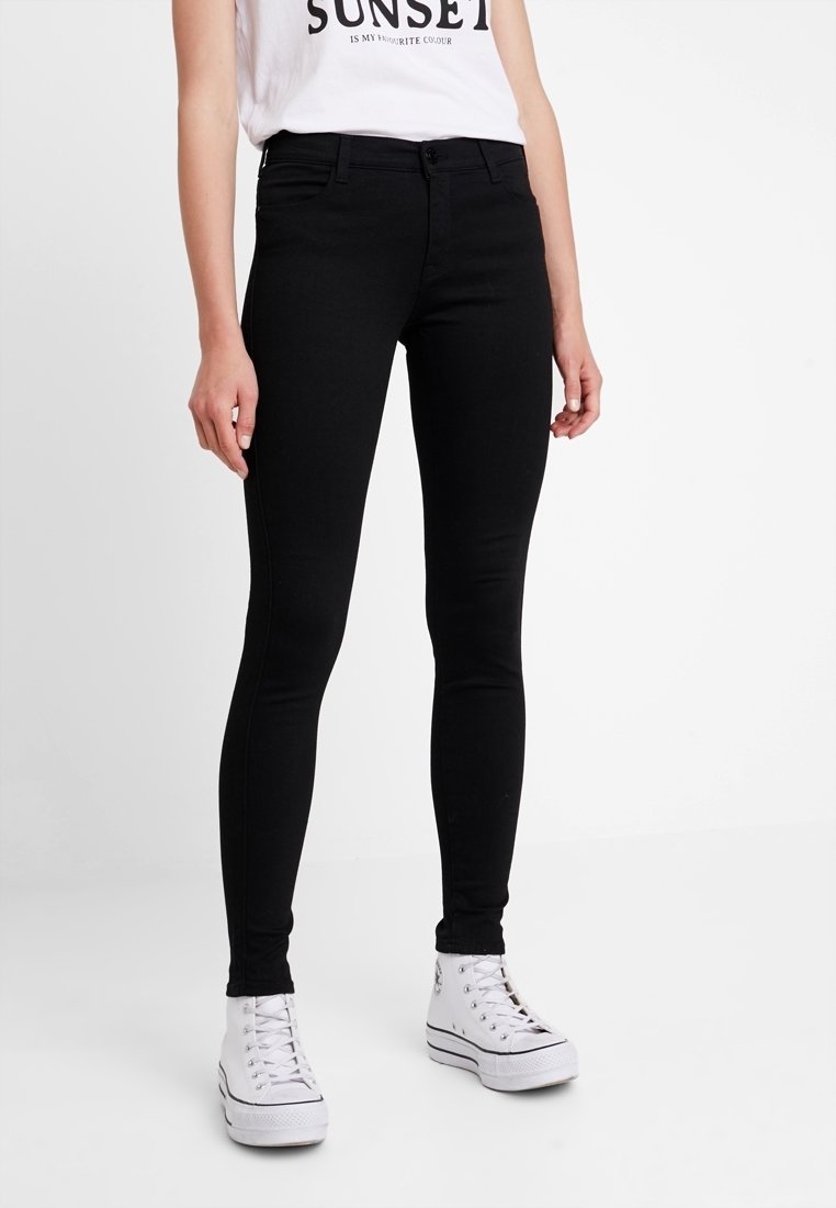 Jeans skinny negros de denim con textura suave. Presenta un diseño clásico de cinco bolsillos, trabillas para cinturón y cierre de cremallera.