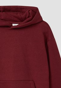 Burgundowa bluza z dużym, miękkim kapturem, ściągaczami przy mankietach oraz kieszenią typu kangur; wykonana z teksturowanej, średniej grubości mieszanki bawełny.