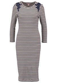 Robe rayée bleu marine et crème, texture ribbed, manches longues, forme ajustée, avec des accents en dentelle florale sur les épaules.